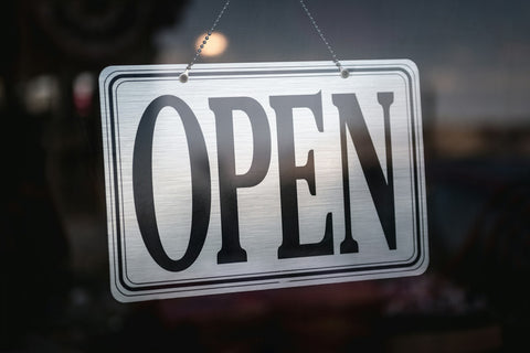 Cartello aperto su porta a vetri di un negozio